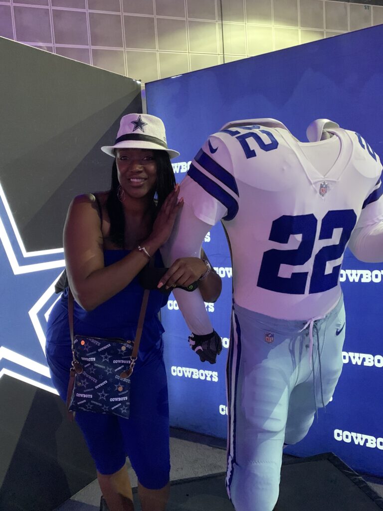 Woman wearing a Dallas Cowboys hat stands next to mannequin dressed as Dallas Cowboys football player